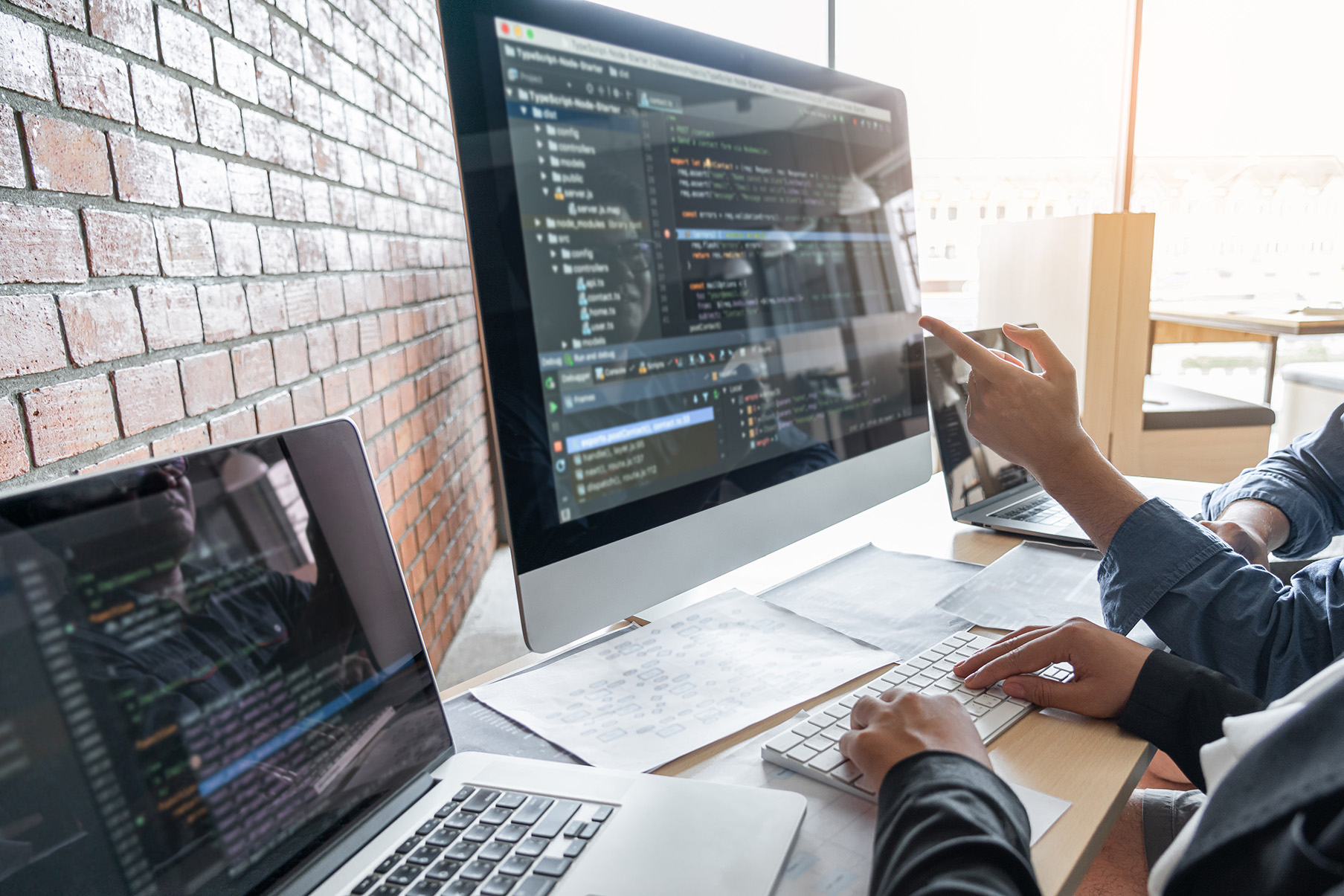 To utviklere samarbeider med å kode, en peker på skjermen mens den andre skriver